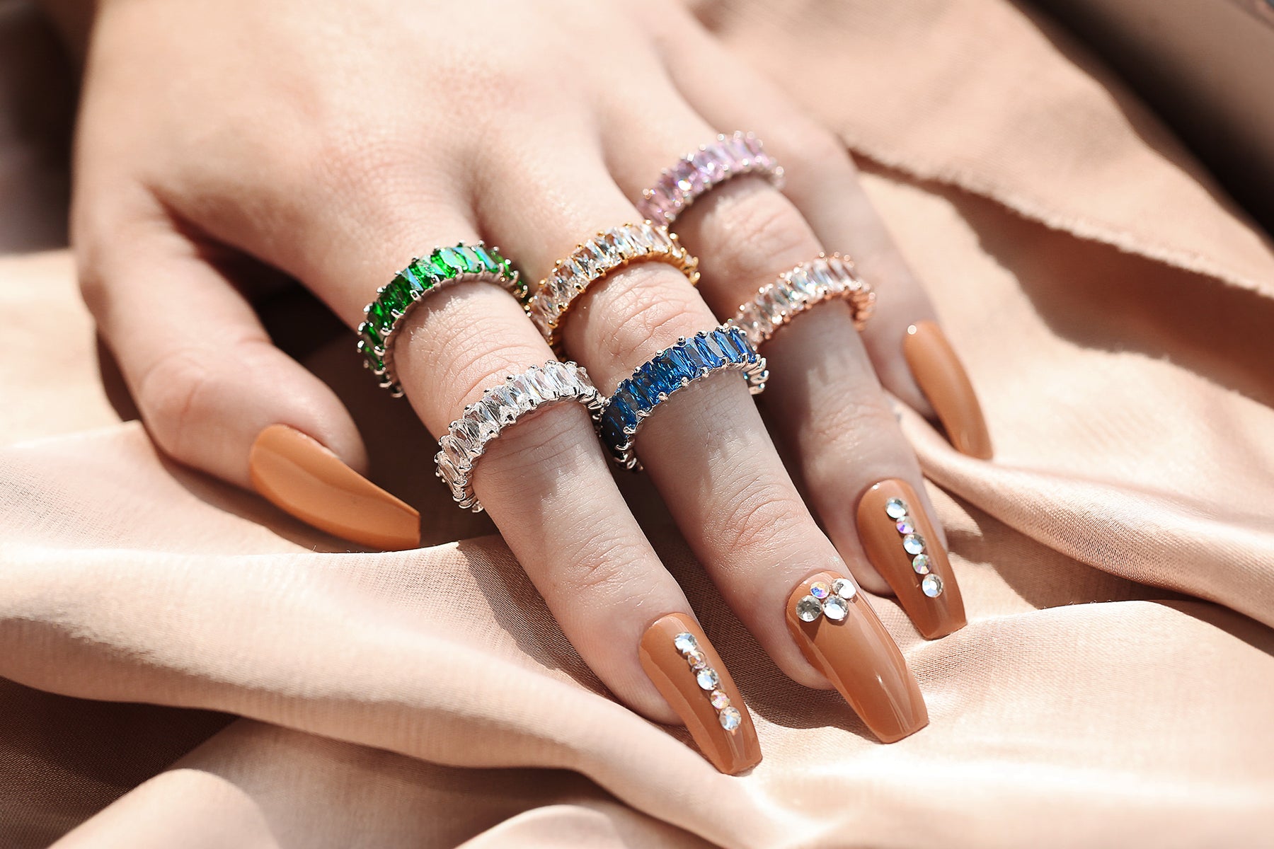 Hand with multiple different colored eternity wedding bands. Shop Wedding Bands